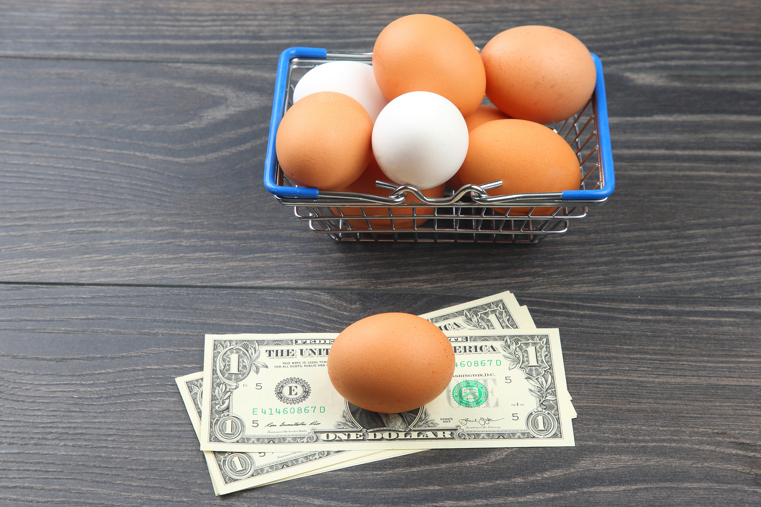 chicken eggs in a supermarket grocery basket against a dollar background on a wooden background. sale and business of food products